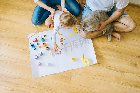 快乐家庭海报摄影照片_快乐的家庭和一只猫画一张海报, 另一只用颜料