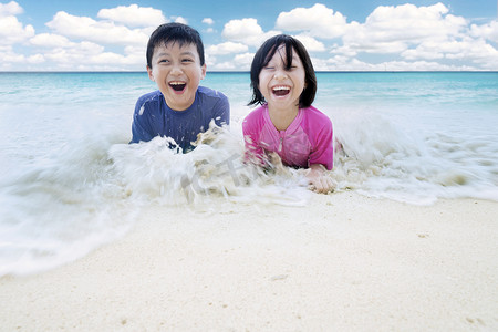 两个小朋友在沙滩上玩浪