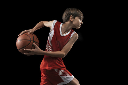 在黑人背景下打篮球的少年的剪影