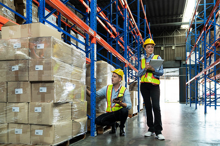 Male and Female Supervisors Hold Digital Tablet is checking the number of items in the warehouse that he is responsible for. checking goods in a warehouse by scanning a barcode.