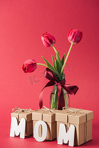 花束红色郁金香在玻璃花瓶和纸字妈妈在红色背景