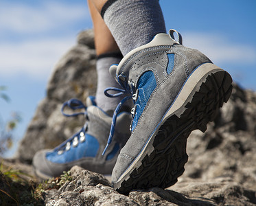 径摄影照片_徒步旅行靴和腿攀爬岩石径的特写