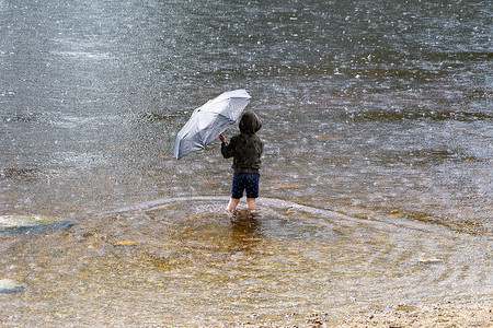 一个男孩拿着雨伞避雨