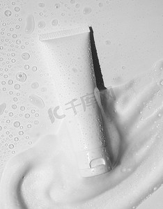 白色塑料管模型与润肤霜，洗发水或面部清洁剂，温和的肥皂泡沫污迹和水滴白色背景，以上。美容美发美容皮肤科产品