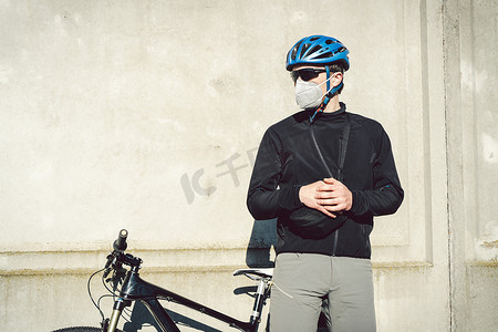 由于城市的烟雾，骑自行车的人戴着面具。自行车快递员送货上门戴着眼镜蛇19号的男人在浓烟浓雾中戴着防污染面罩的骑自行车者.派递服务.