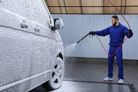 洗车汽车摄影照片_洗车时用泡沫覆盖汽车的工人