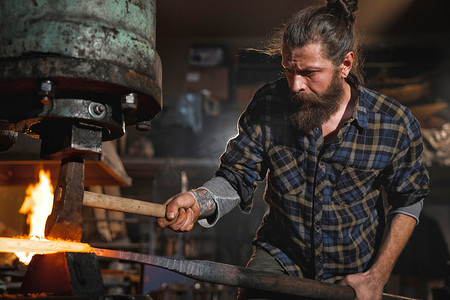 真正残忍的铁匠在车间里工作, 用红热的铁锤做机械锤子。职业肖像.