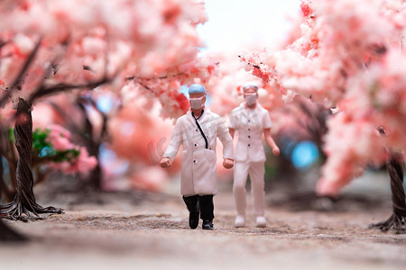 粉色温馨小清新摄影照片_樱花树林中的医护人员