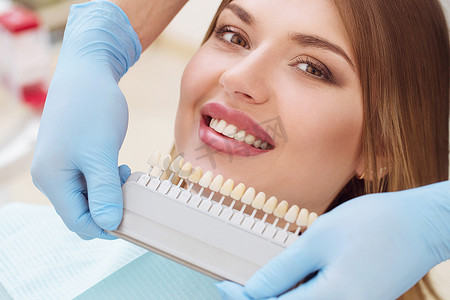 美丽的欧洲女人带着健康的牙齿面带微笑.牙科护理的概念。一组不同色调的植入物