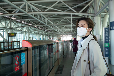 戴口罩的年轻女人站在地铁站台上