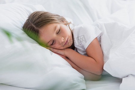 女孩躺在白色被褥上睡觉的选择性焦点
