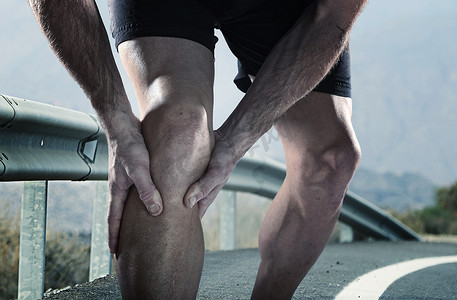 运动腿抱着膝盖痛苦受难肌肉损伤运行的年轻体育人 