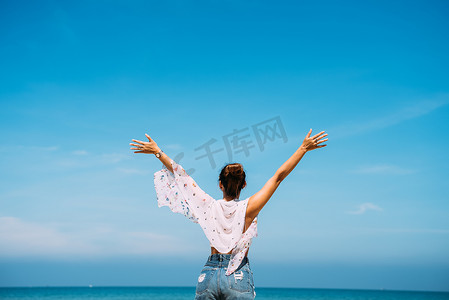 炎炎夏日，站在那里，抱着胳膊的女人欣赏着美丽的海滨大海