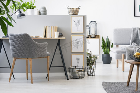 灰色椅子的真实的相片站立由木桌与书在半墙壁以简单的剪影在明亮的客厅内部
