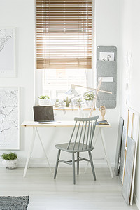 灰色木椅站在办公桌旁, 用台灯和笔记本电脑, 在白色房间内设有窗户和新鲜植物的空屏幕。