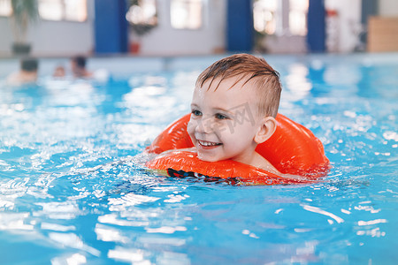 在游泳池里的白种白人孩子的肖像。学龄前男孩的训练, 漂浮在水中的红色圆圈环。健康积极的生活方式