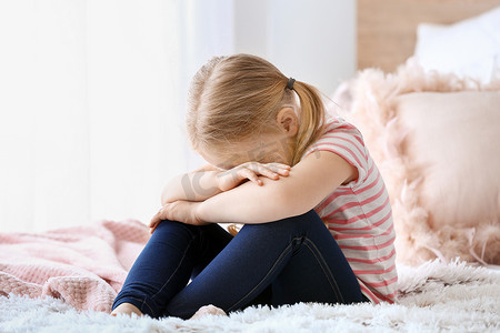 暴风哭泣摄影照片_哭泣的小女孩坐在床上
