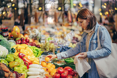 女人在食品市场选择水果和蔬菜。可重复使用的环保袋购物。可持续的生活方式。生态友好理念. 