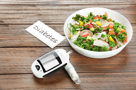 钢笔摄影照片_数字血糖, 柳叶刀钢笔和碗沙拉在桌上。糖尿病饮食