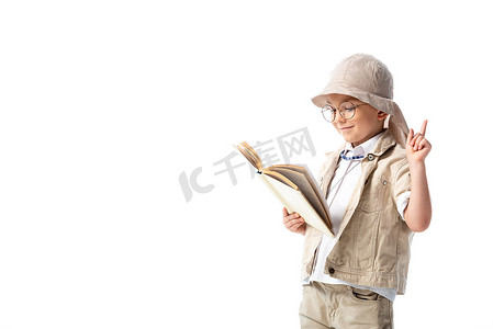 书籍标志摄影照片_专注微笑的探险家孩子在眼镜阅读书籍,并显示想法标志隔离在白色