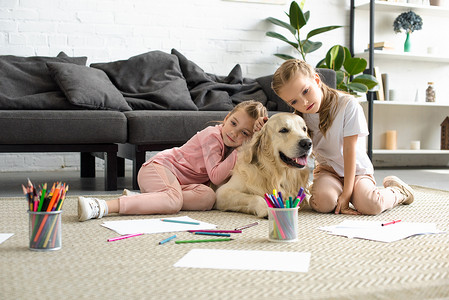 抱狗摄影照片_可爱的孩子抱着金色猎犬的狗, 而坐在地板上在家