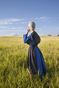 阿米什人的女人站在绿草如茵的球场上与午后的阳光