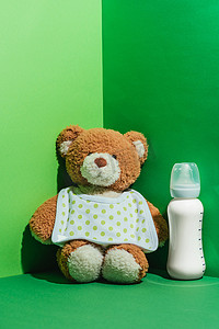 泰迪熊和婴儿奶瓶与牛奶在绿色