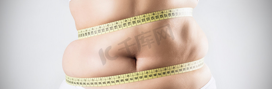 体重增加的女人测量她的肥胖腹部.