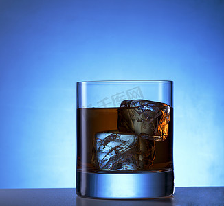 杯子加冰块摄影照片_威士忌加冰块的杯子