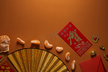 剥皮的橘子, 在棕色背景上有象形文字和红色信封的扇子的顶视图