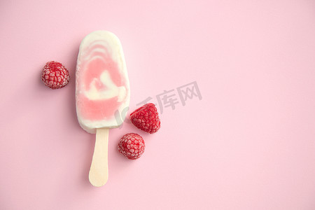 浆果雪糕和酸奶冰棒与覆盆子在淡粉色背景