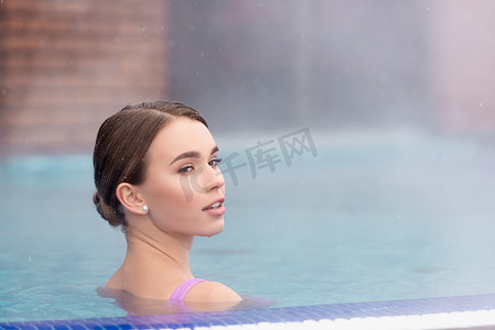 室外温泉摄影照片_年轻女子望着远方，在室外温泉池中洗澡 