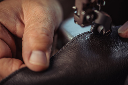 缝纫剪影摄影照片_缝纫机上鞋匠缝制真皮的剪影