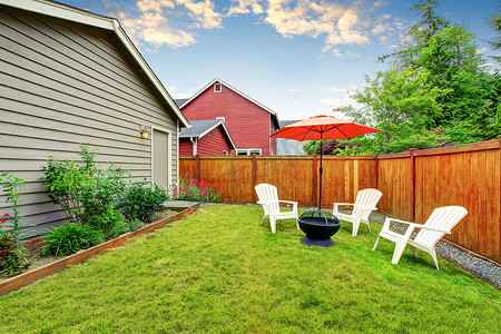 篱笆后院庭院与打开的红伞，保存良好的草坪