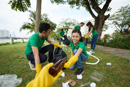 捡垃圾摄影照片_亚洲志愿者组捡垃圾进大垃圾袋