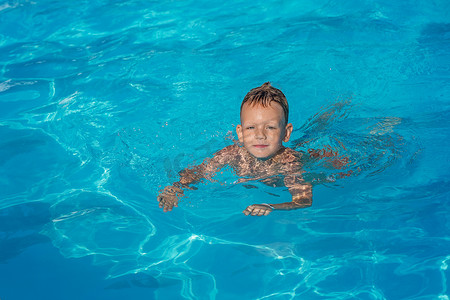 快乐孩子在玩蓝色水的游泳池.