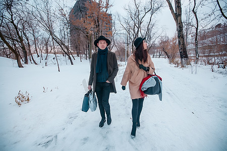 Young hipster beautiful couple in black hats in the winter forest,love,winter vacation in mountains,jeans,warm coat,traveling,hiking,winter walk in love,man in a green coat.girl in a beige coat