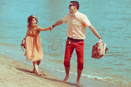 沙滩上散步的情侣。快乐的年轻人结婚时尚及膝