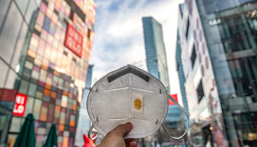 城市背景下的建筑摄影照片_城市背景下的N95口罩