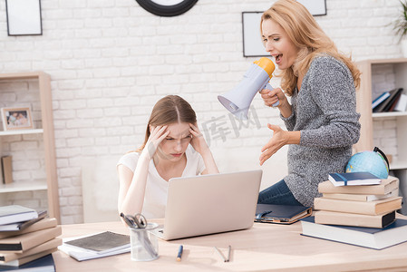 妈妈责备她的女儿在笔记本电脑上做得不好。女儿不能正确地完成学校的作业。这个女人因此而生气。她对着女儿尖叫.