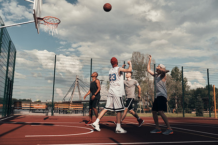 户外运动老外摄影照片_运动服装青年男子组在户外打篮球