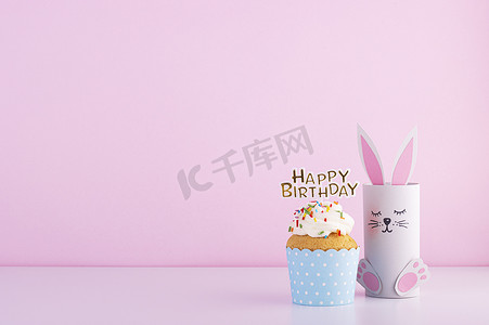 可爱的纸兔和美味美丽的蛋糕蛋糕生日粉红背景。生日宴会的背景