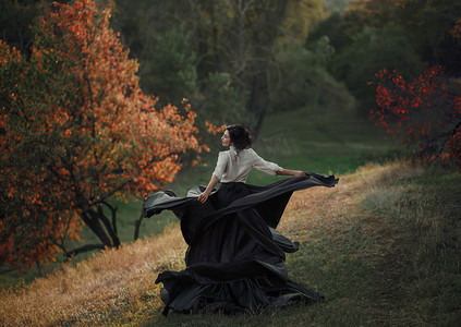 一个穿着老式连衣裙的女孩在山上打转。背景狂放的自然。自由的滋味。艺术摄影