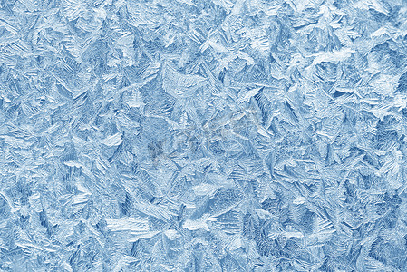 磨砂玻璃玻璃摄影照片_在冬天的霜在窗户玻璃上的图案。磨砂玻璃纹理。蓝色