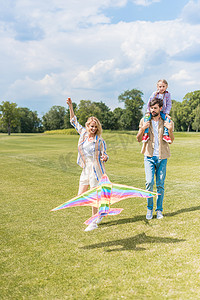 快乐的年轻父母和可爱的小女儿玩五颜六色的风筝在公园里 