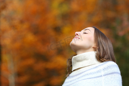 呼吸新鲜空气摄影照片_秋天，在美丽的公园或森林里呼吸新鲜空气的松驰的女人