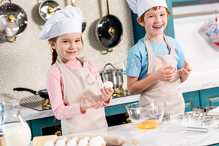一起看看表情包摄影照片_可爱的快乐的孩子在厨师帽子和围裙微笑, 而在厨房做面团一起