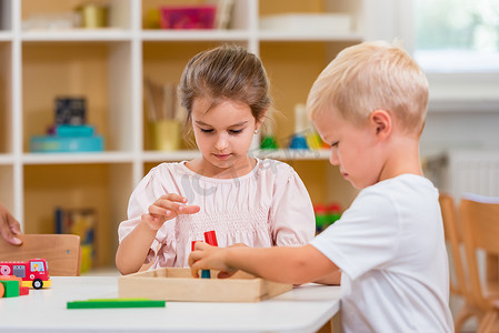 有几个孩子在幼儿园玩五彩缤纷的木制玩具。他们全神贯注于玩耍.