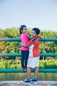 亚洲的孩子们向后看, 互相拥抱。亲切的兄弟在锻炼以后放松与他的姐妹, 室外在夏天天。锻炼身体健康的概念。老式胶片过滤效果.