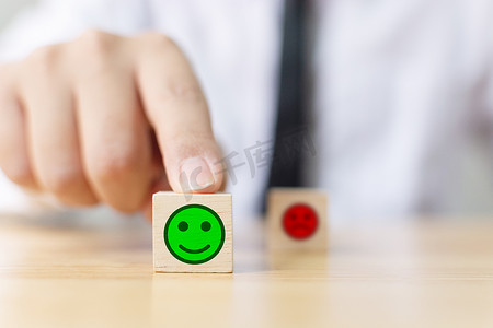 实业家的手在木块立方上选择笑脸，最佳优秀的业务服务评价客户体验，满意度调查概念
